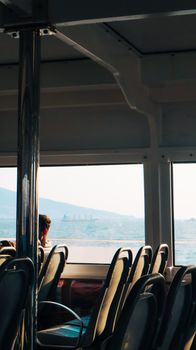 View from a ferry with sunlit seats and ocean in the distance.
