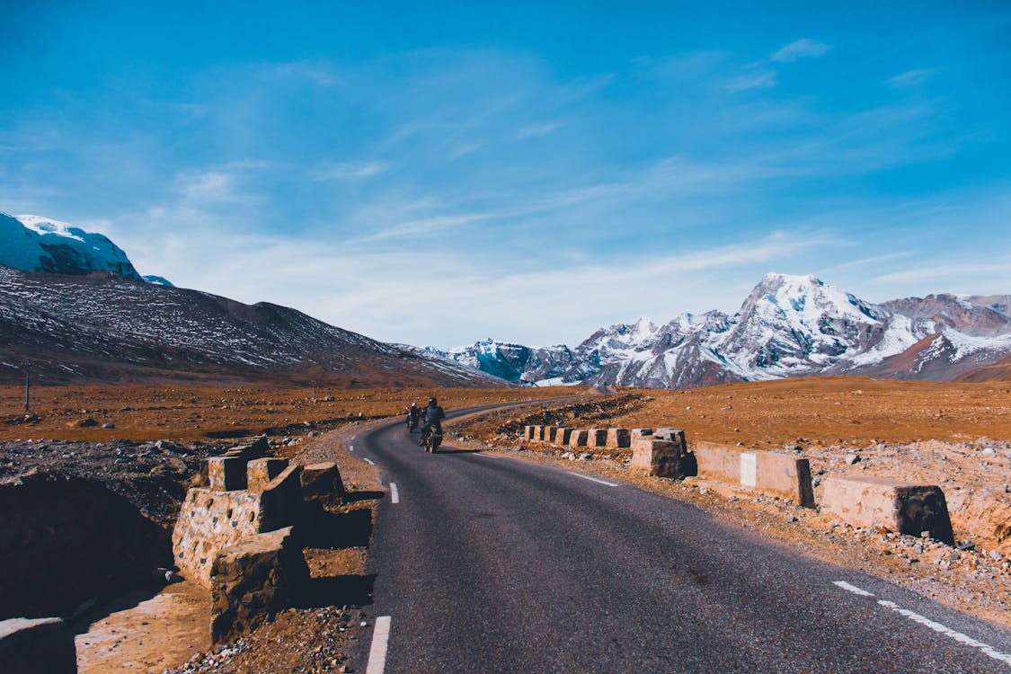 People Riding On Motorcycles On An Asphalt Road