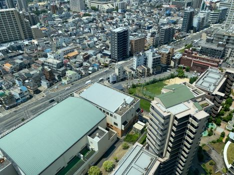 Aerial view of a dense urban cityscape with residential and commercial buildings in bright daylight.