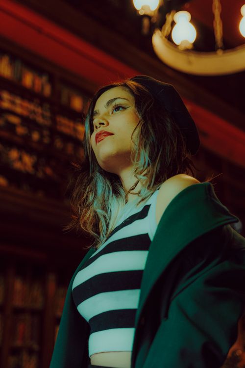 Free Portrait of a fashionable woman wearing a beret and striped top in a warmly lit indoor setting. Stock Photo