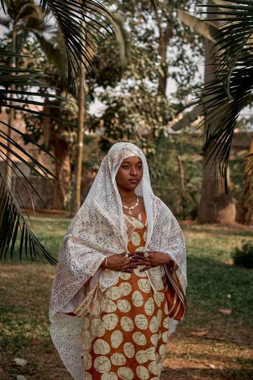 Free A woman in vibrant African attire stands gracefully amidst lush outdoor greenery. Stock Photo