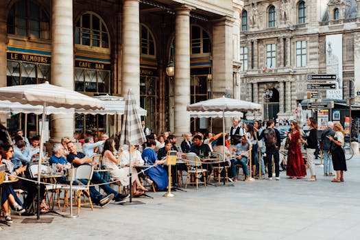 Enjoy the lively outdoor ambiance at the famous Paris café, Le Nemours, with bustling crowds under sunny skies.