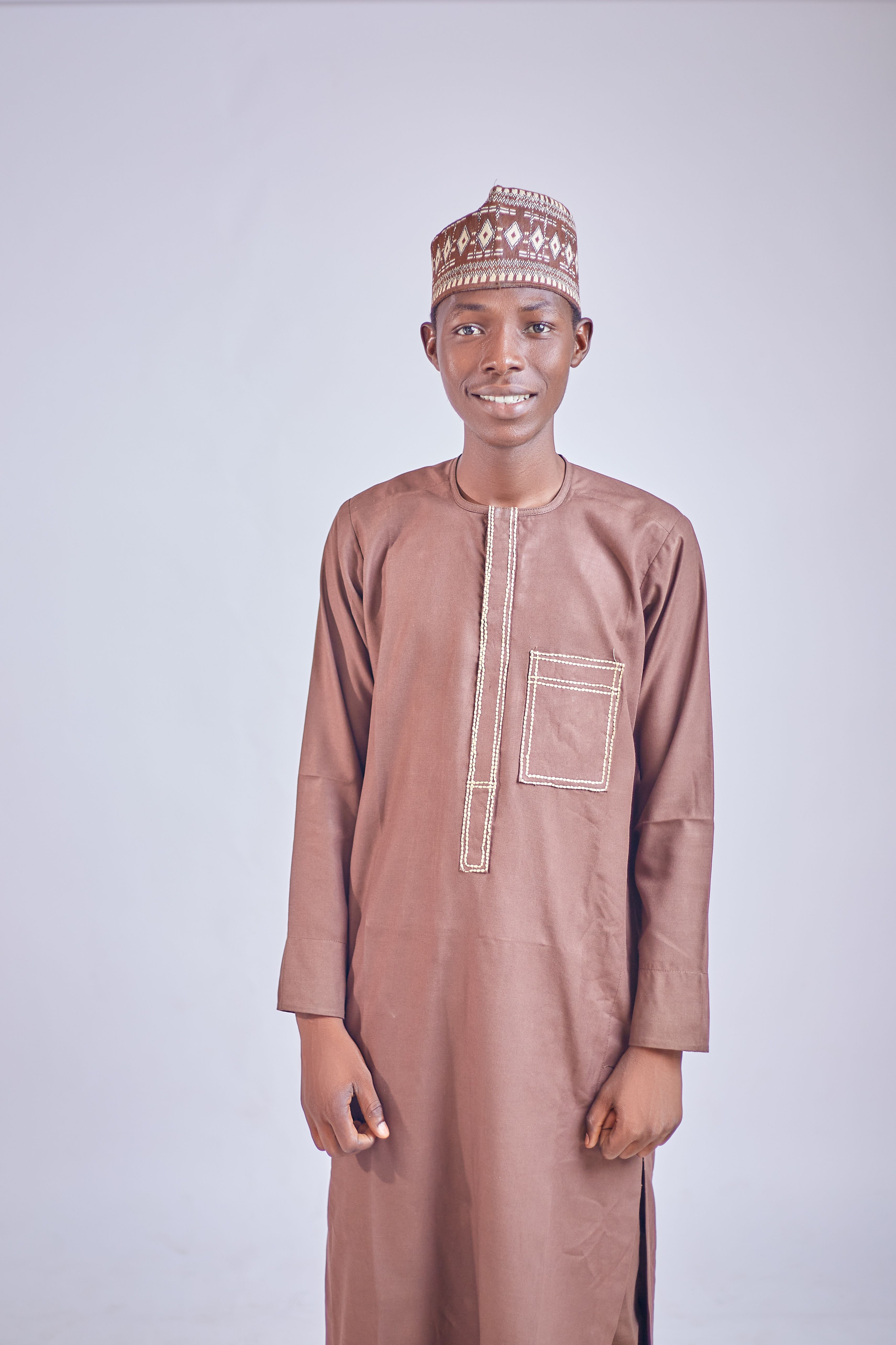 Portrait of a young man wearing traditional brown cultural attire and hat.