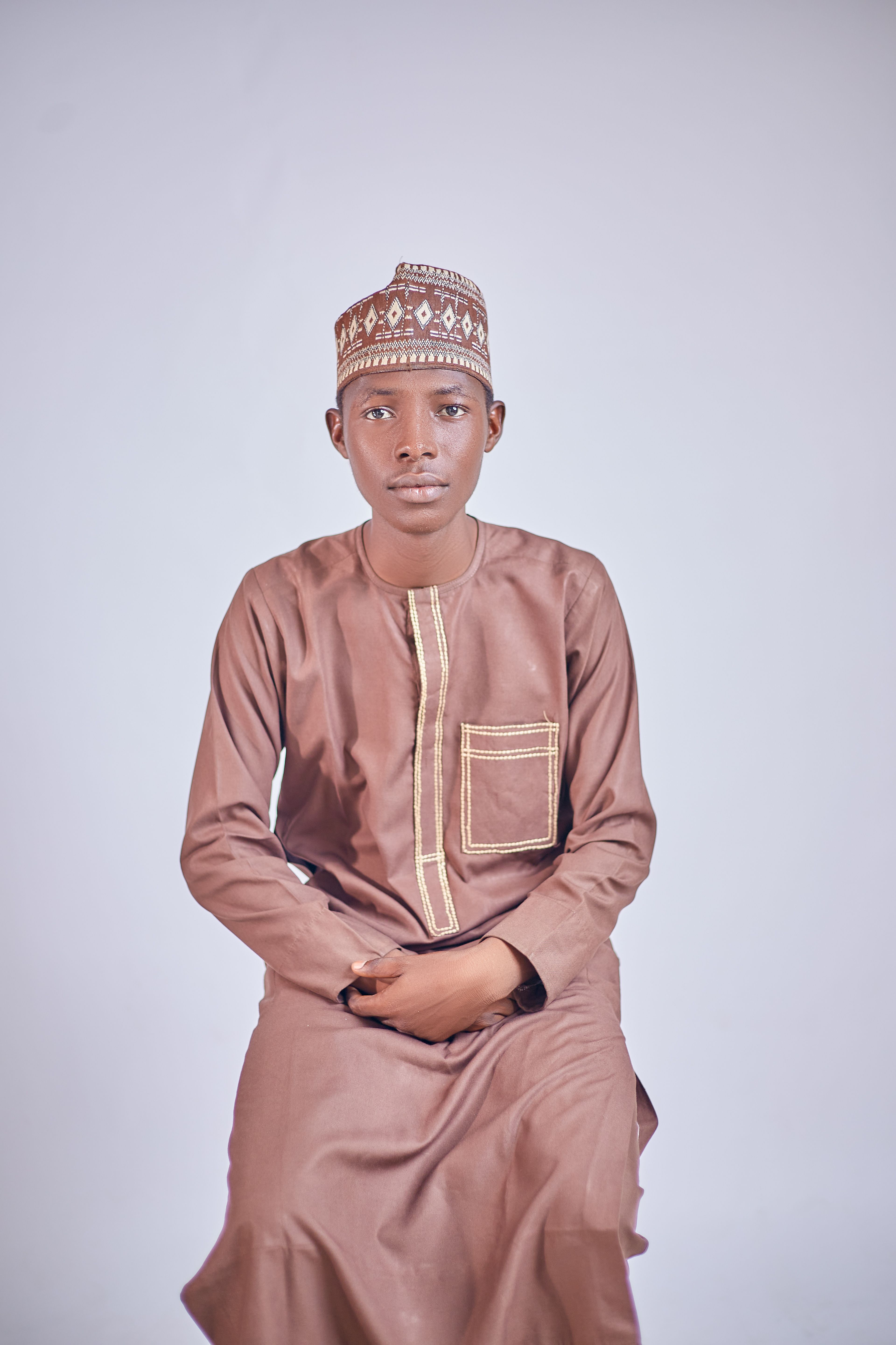 Portrait of a young man in traditional attire with a neutral background.