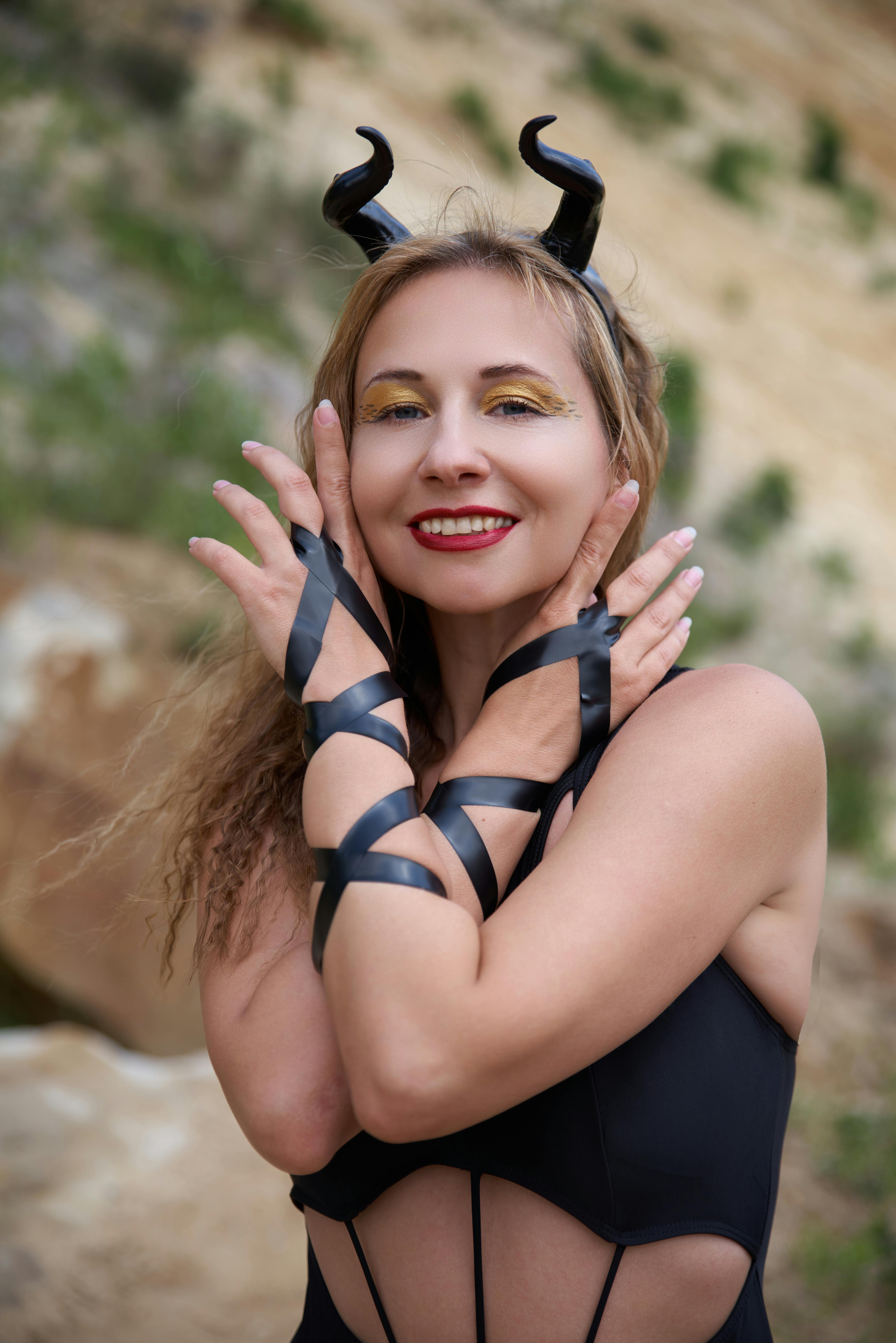 Gratuit Portrait d'une femme souriante en costume de diable, en extérieur, avec des expressions ludiques. Photos