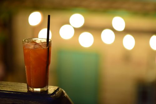 Free A vibrant iced cocktail with straw against warm bokeh background, perfect for summer evenings. Stock Photo