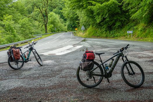 Two bicycles parked on a forest road, surrounded by lush greenery, ideal for travel and adventure enthusiasts.