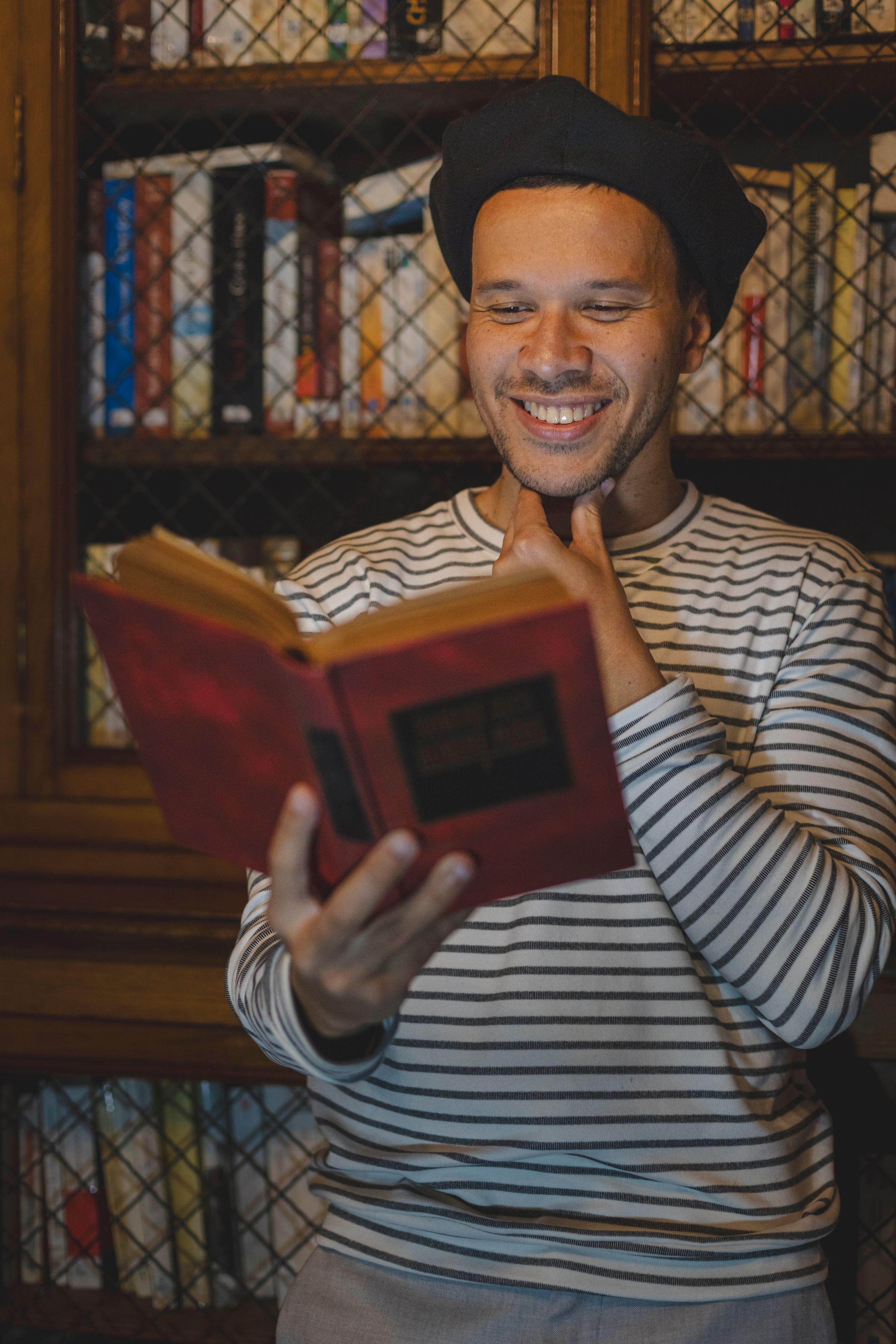 A smiling man enjoying a book in a warm, cozy library atmosphere.