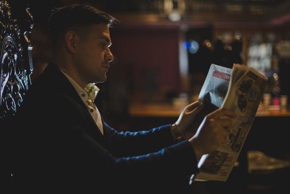 Stylish man enjoys a quiet moment reading a newspaper in a cozy Buenos Aires café setting.