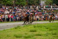 Vibrant scene of horse racing at Bac Ha festival in Lào Cai, Vietnam against a lively crowd.