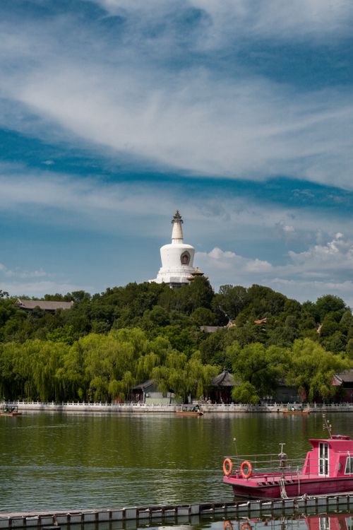 Free Beautiful summer view of the White Pagoda in Beihai Park, Beijing, with lush greenery and serene water. Stock Photo