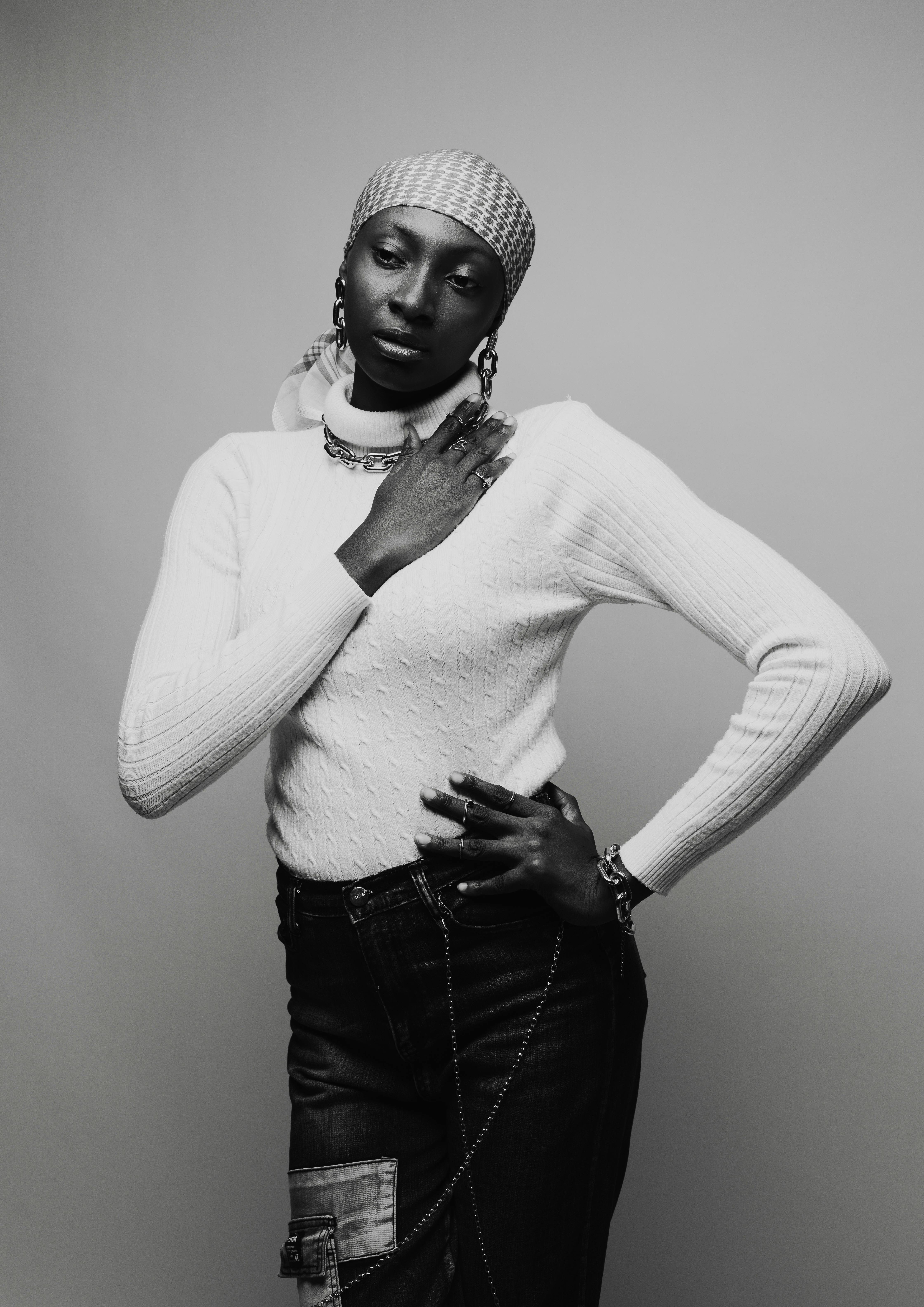 Black and white portrait of a woman in a stylish outfit with a confident pose.