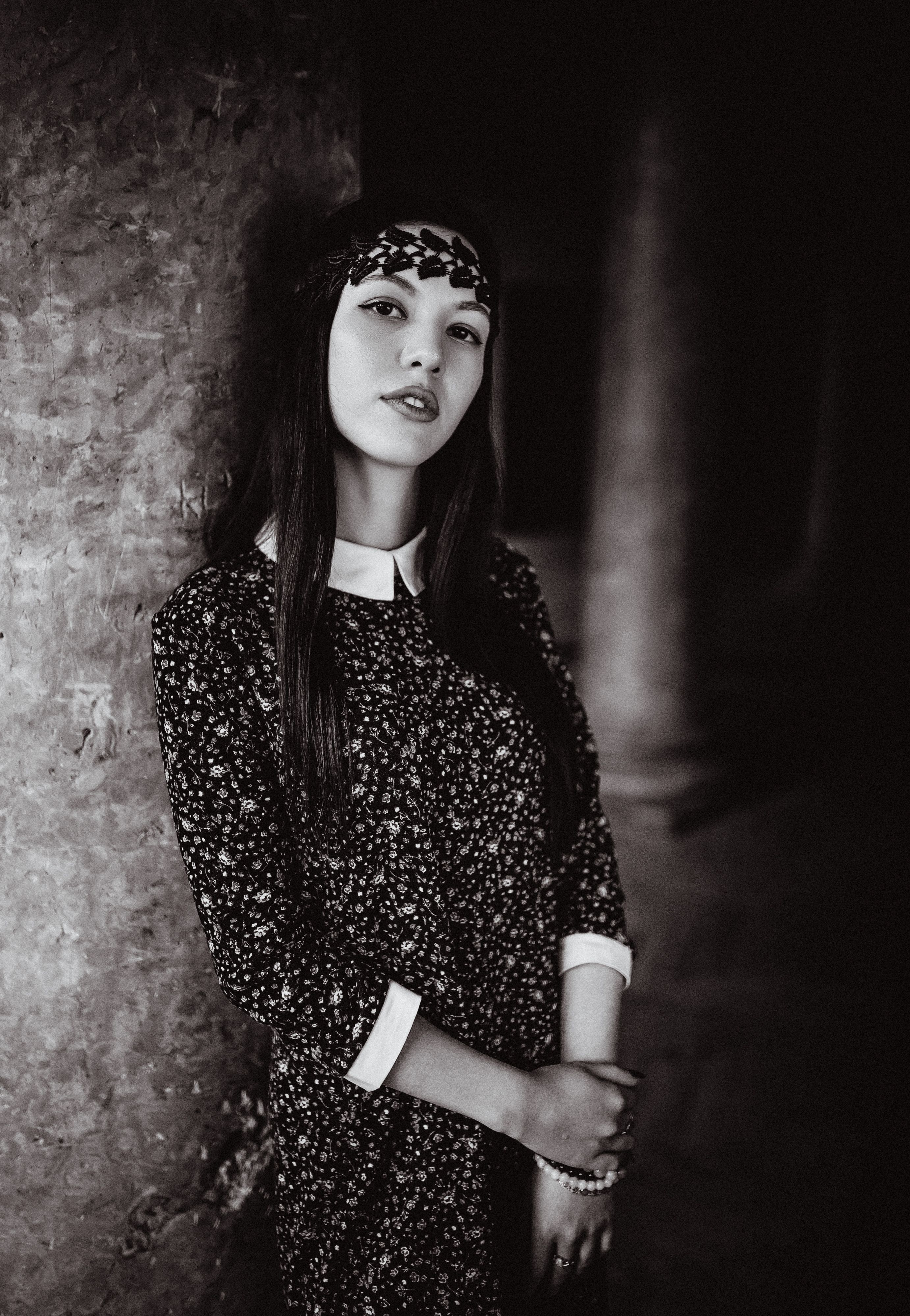 A vintage-style black and white portrait of a woman in dramatic lighting and floral dress.