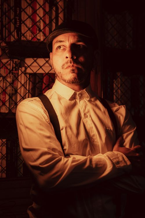 Free Vintage-style portrait of a man in a library setting with warm, dramatic lighting. Stock Photo