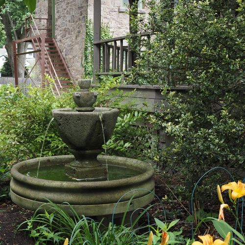 Free Elegant stone fountain surrounded by lush greenery in Lambertville, New Jersey garden. Stock Photo