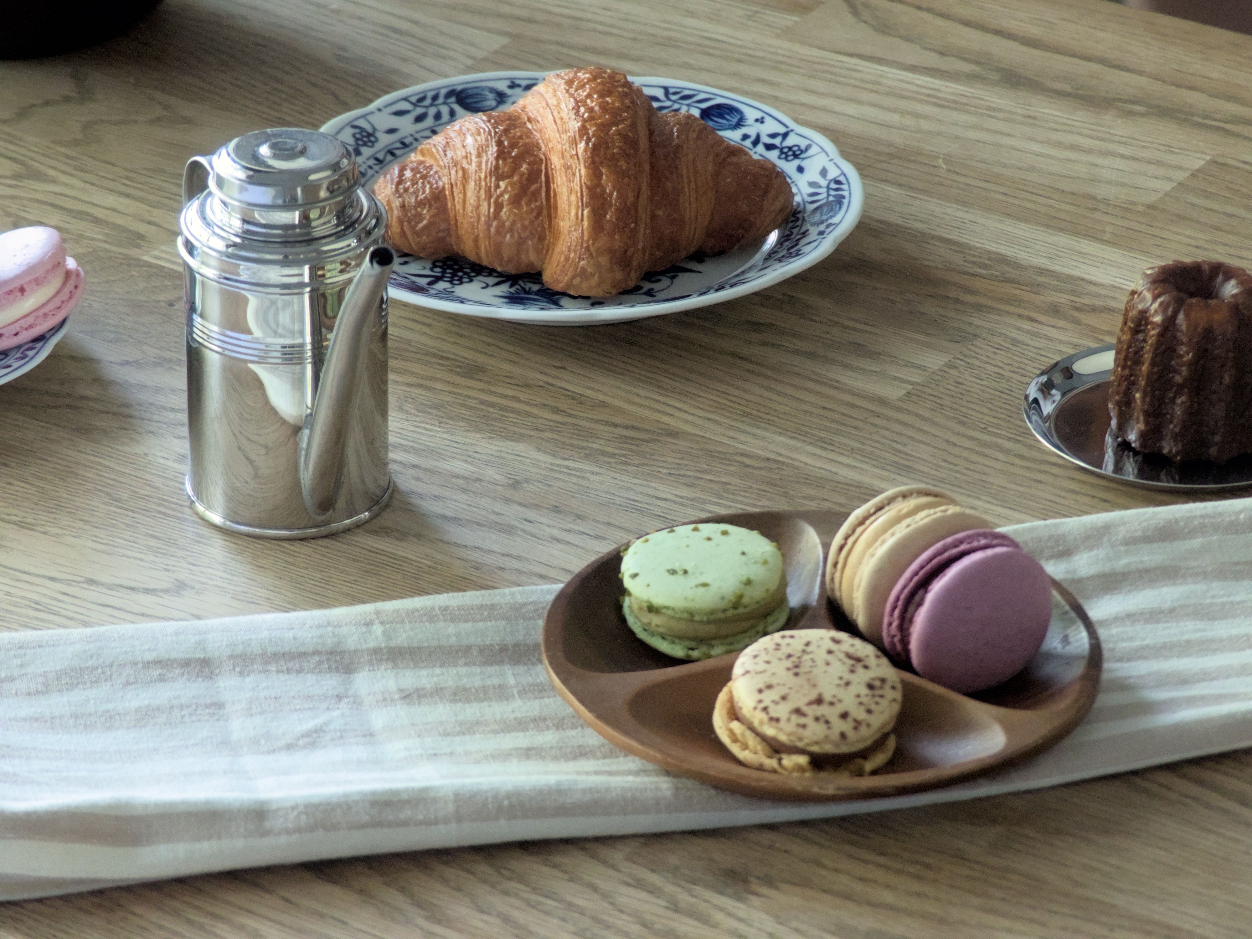 A delightful selection of French pastries and macarons on a wooden table, perfect for breakfast.