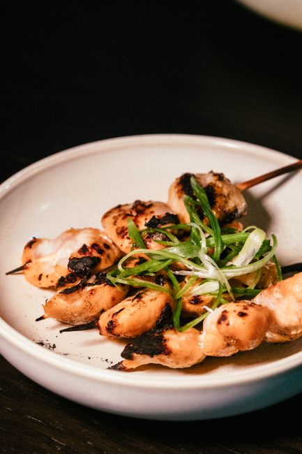 Delicious grilled chicken skewers with green onions on a ceramic plate, perfect for a delightful meal.