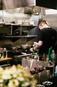 Chef preparing a meal in a professional kitchen with modern equipment.