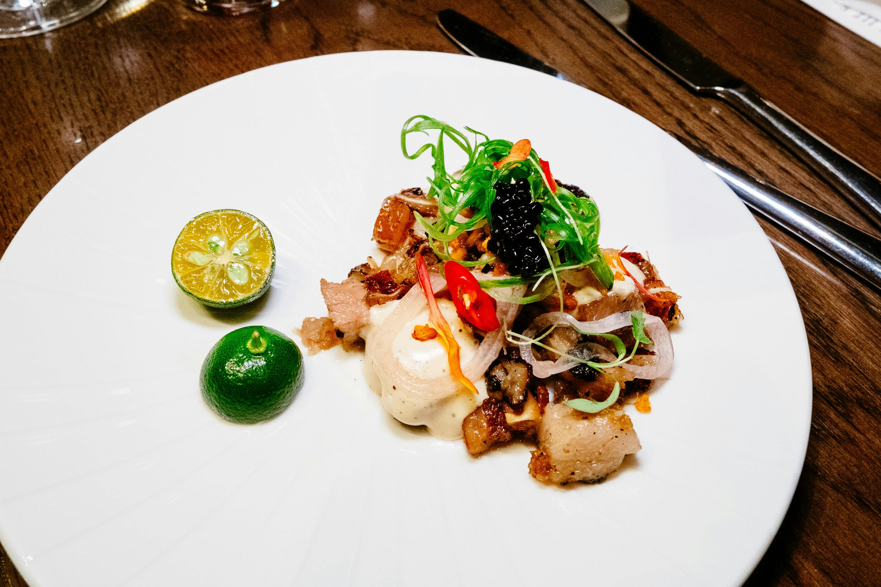 Delicious gourmet sisig with kalamansi served on a white plate.