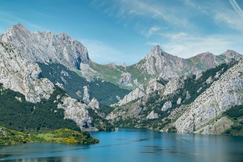 Free Breathtaking view of a serene mountain lake surrounded by rocky peaks under a clear blue sky. Stock Photo