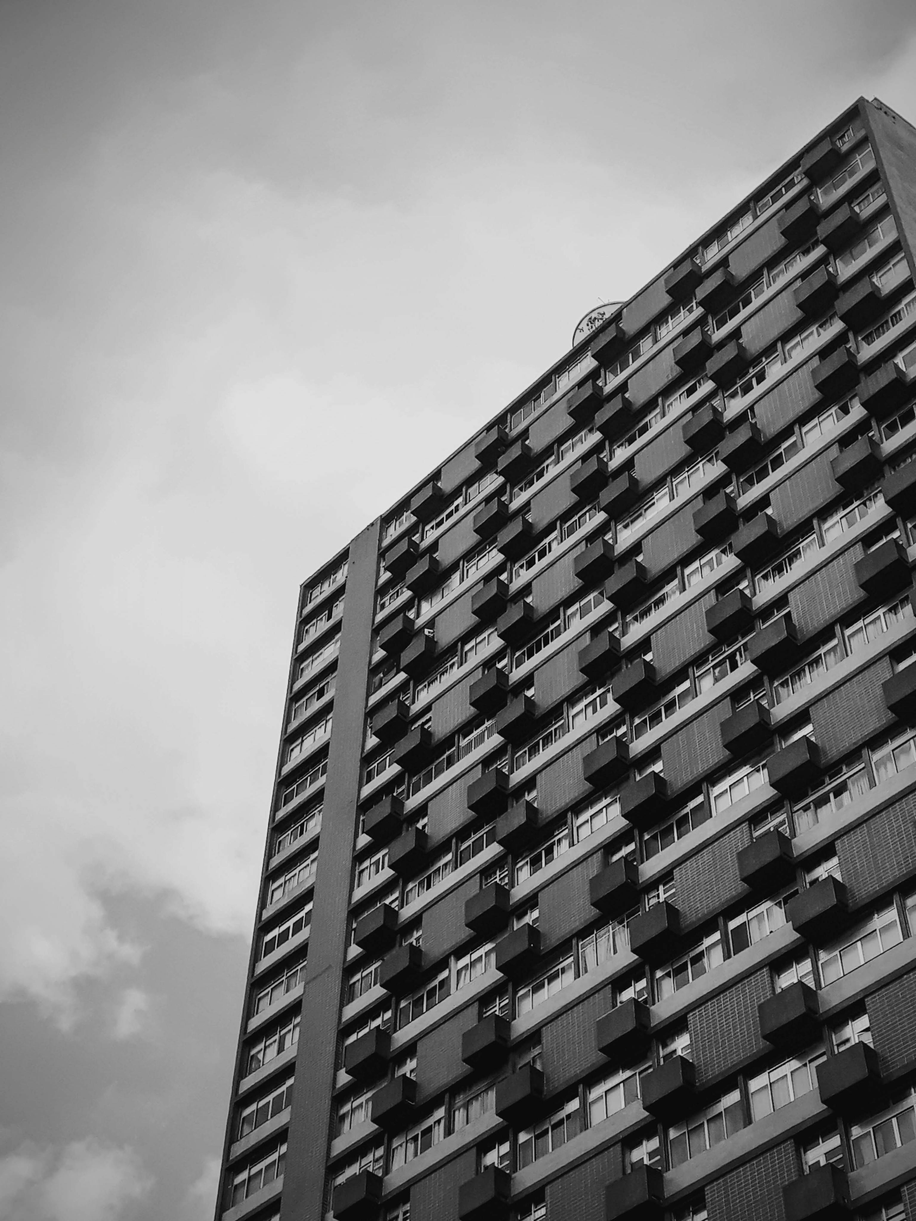 一张戏剧性的黑白图像，展示了带有几何阳台的高层建筑