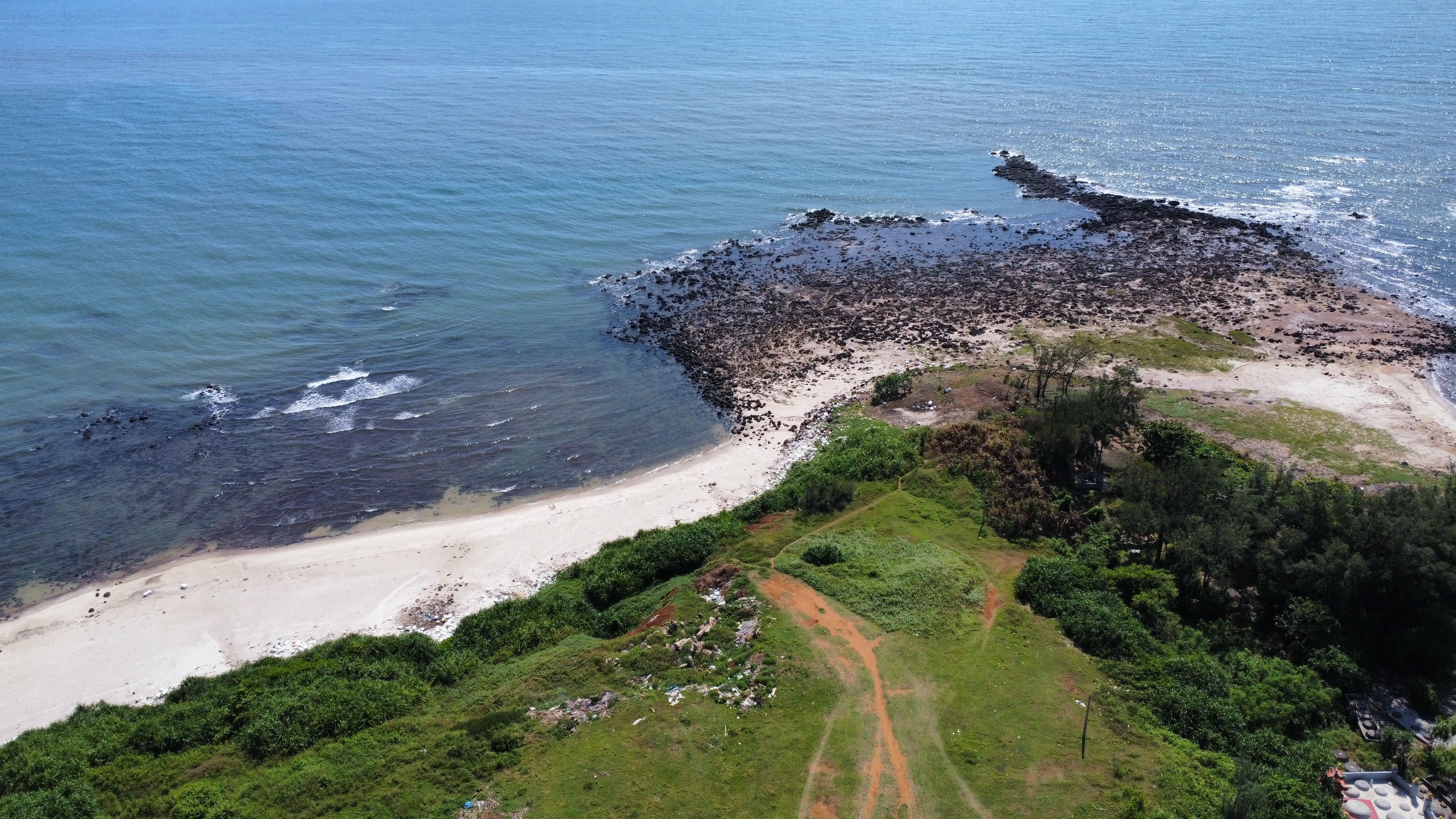 A scenic aerial view of a secluded beach with rocky shorelines and lush greenery.