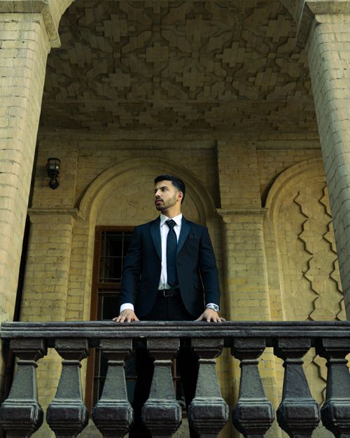 Free Confident man in suit stands on historic balcony, exuding authority. Stock Photo