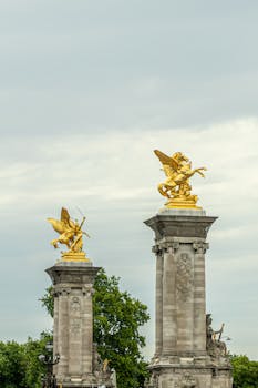 Golden statues atop columns on Pont Alexandre III, Paris, an iconic French landmark.