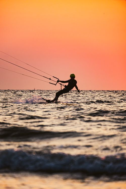 Free Silhouette of a kitesurfer gliding over waves during a vibrant sunset in Middelkerke, Belgium. Stock Photo