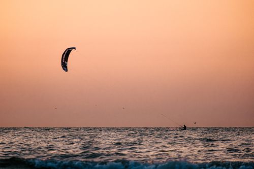 Free Kitesurfer gliding across the waves during a stunning sunset in Middelkerke, Belgium. Stock Photo