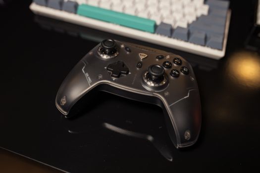 Game controller resting on a desk next to a keyboard, showcasing sleek design in a gaming setup.