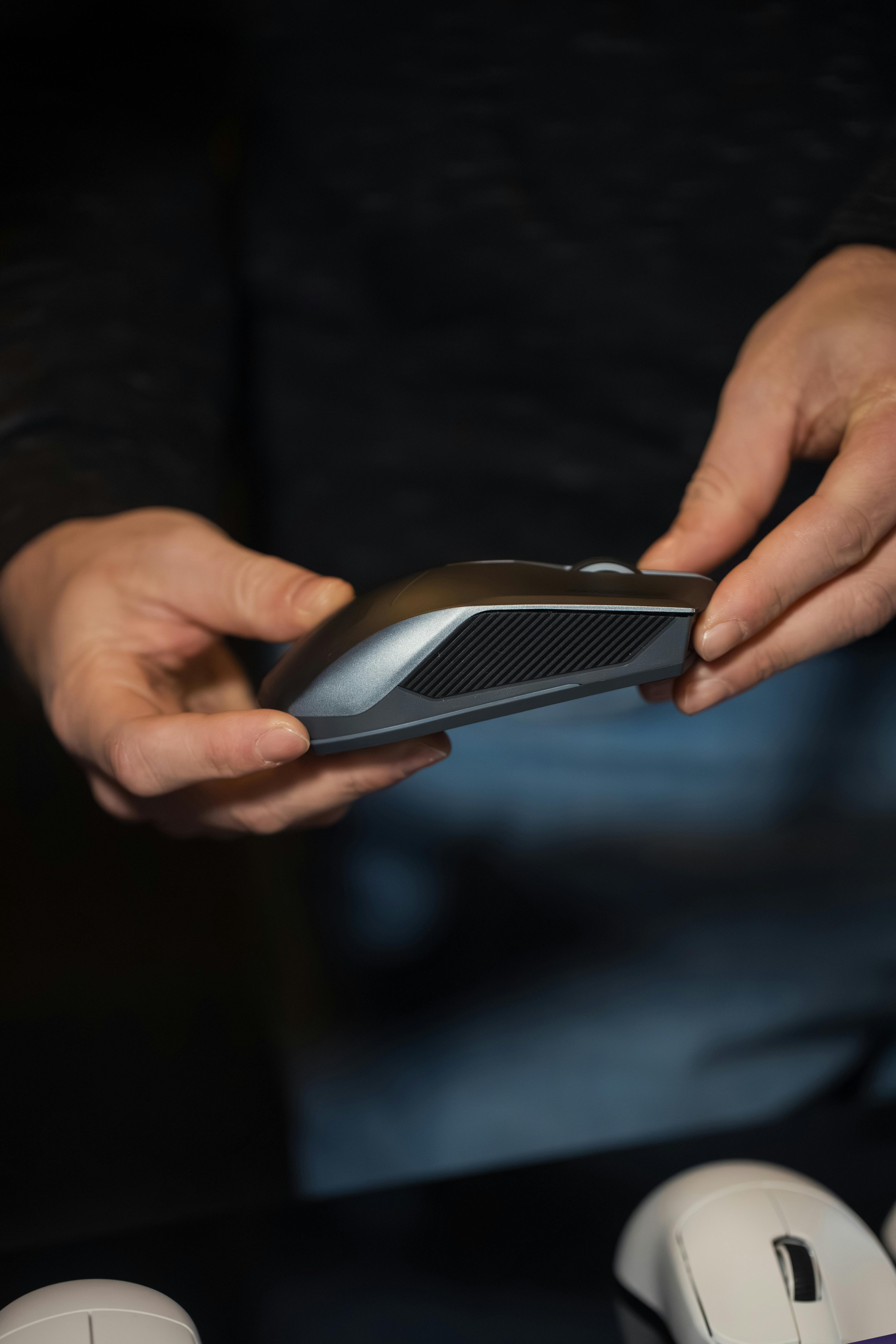 grátis Foto focada em mãos segurando um mouse de computador elegante, adequado para temas de escritório e tecnologia. Foto profissional