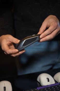 Close-up of a person examining an ergonomic wireless mouse, highlighting technology use.