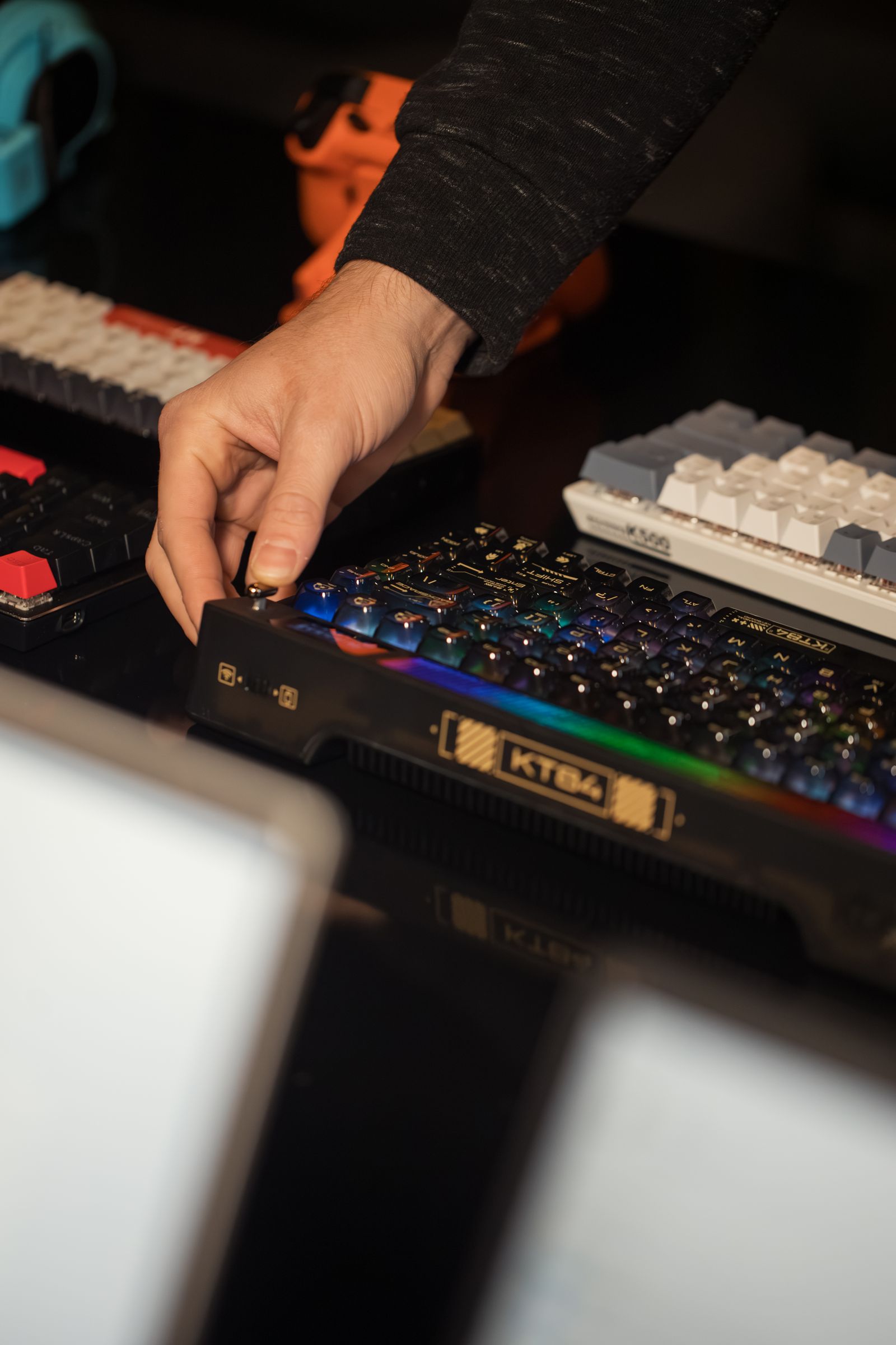 Person adjusting an illuminated mechanical gaming keyboard on a desk
