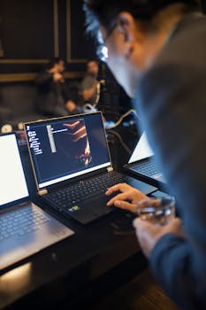 Focused IT professional working on laptop coding in a dimly lit office setting.