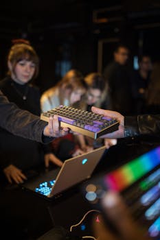 A group of people engaged in a tech event, featuring colorful mechanical keyboards and laptops.