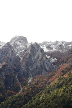 Scenic view of a mountain range with autumn foliage and snowcapped peaks in a natural setting.
