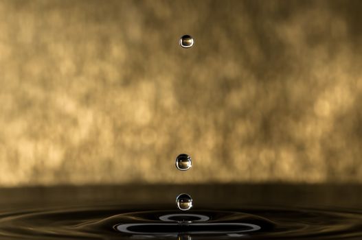 Artistic macro shot of water droplets against a gold background showcasing reflection and intricate detail.