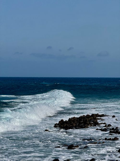 Free Powerful waves crash on the rocky coastline of Lanzarote, Canary Islands, under a clear blue sky. Stock Photo