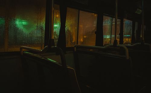 Free Rainy night view from inside an empty bus, showcasing moody urban lights. Stock Photo