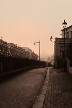 Misty sunrise in a quiet street of historic Rochester, England, featuring Victorian architecture.