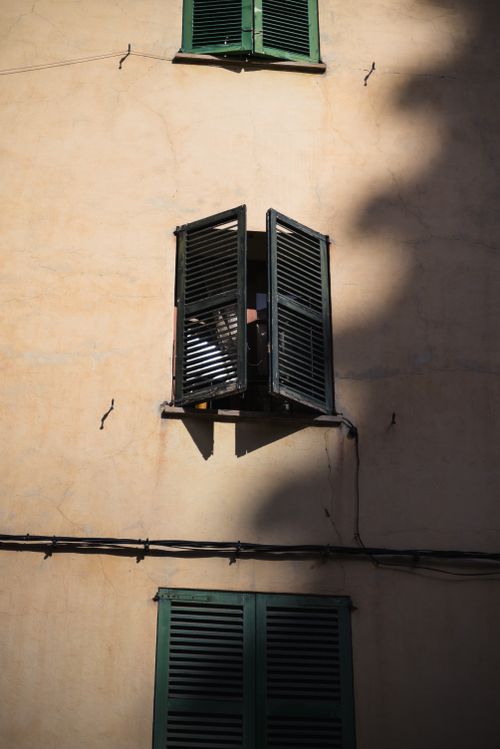 Free A traditional Balearic house facade with green shutters casting dramatic shadows. Stock Photo