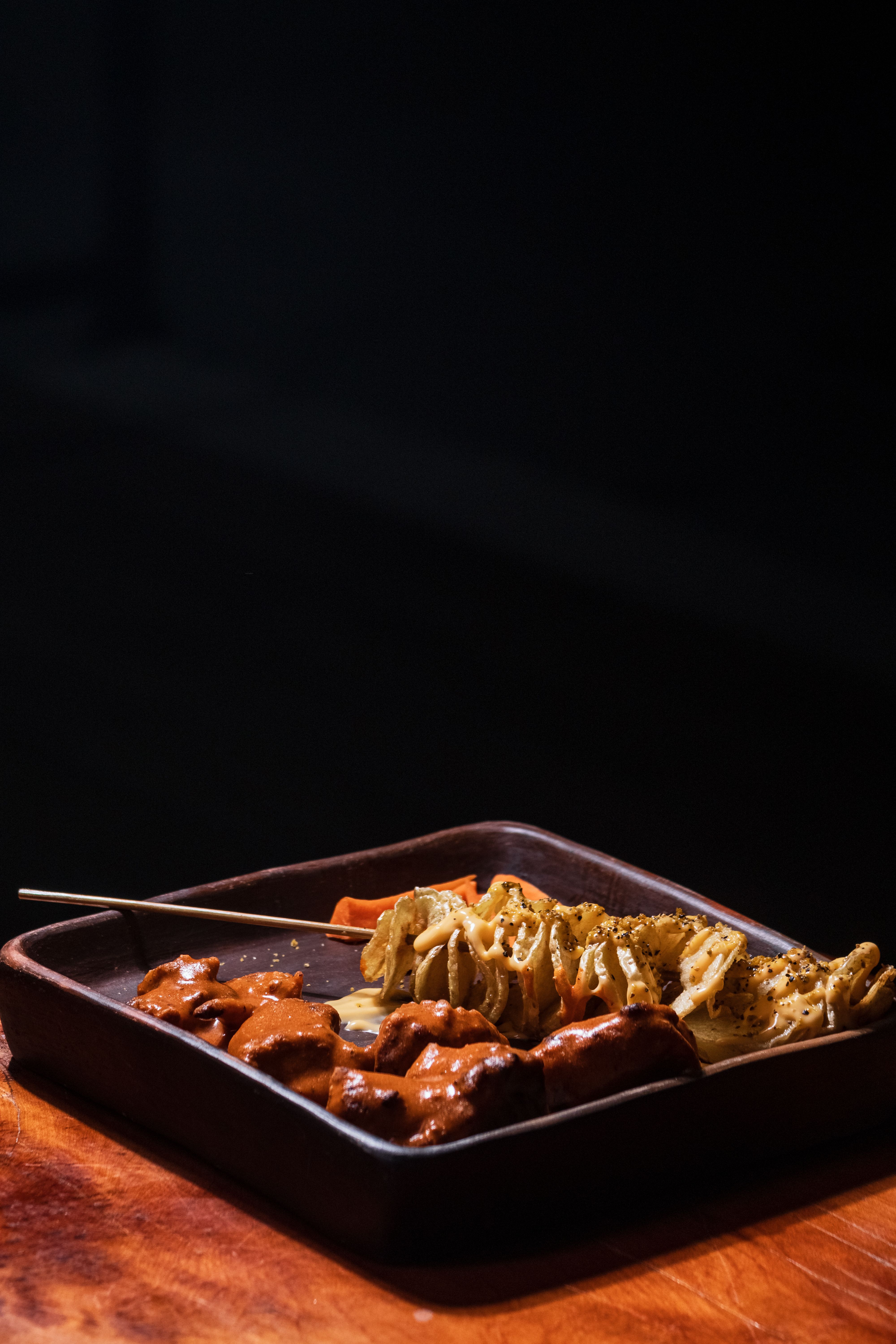 Delicious grilled skewers of meat and vegetables on a dark plate, perfect for barbecue lovers.