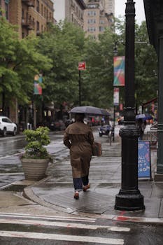 A person walks with an umbrella on a rainy day in Greenwich Village, capturing NYC's charm.