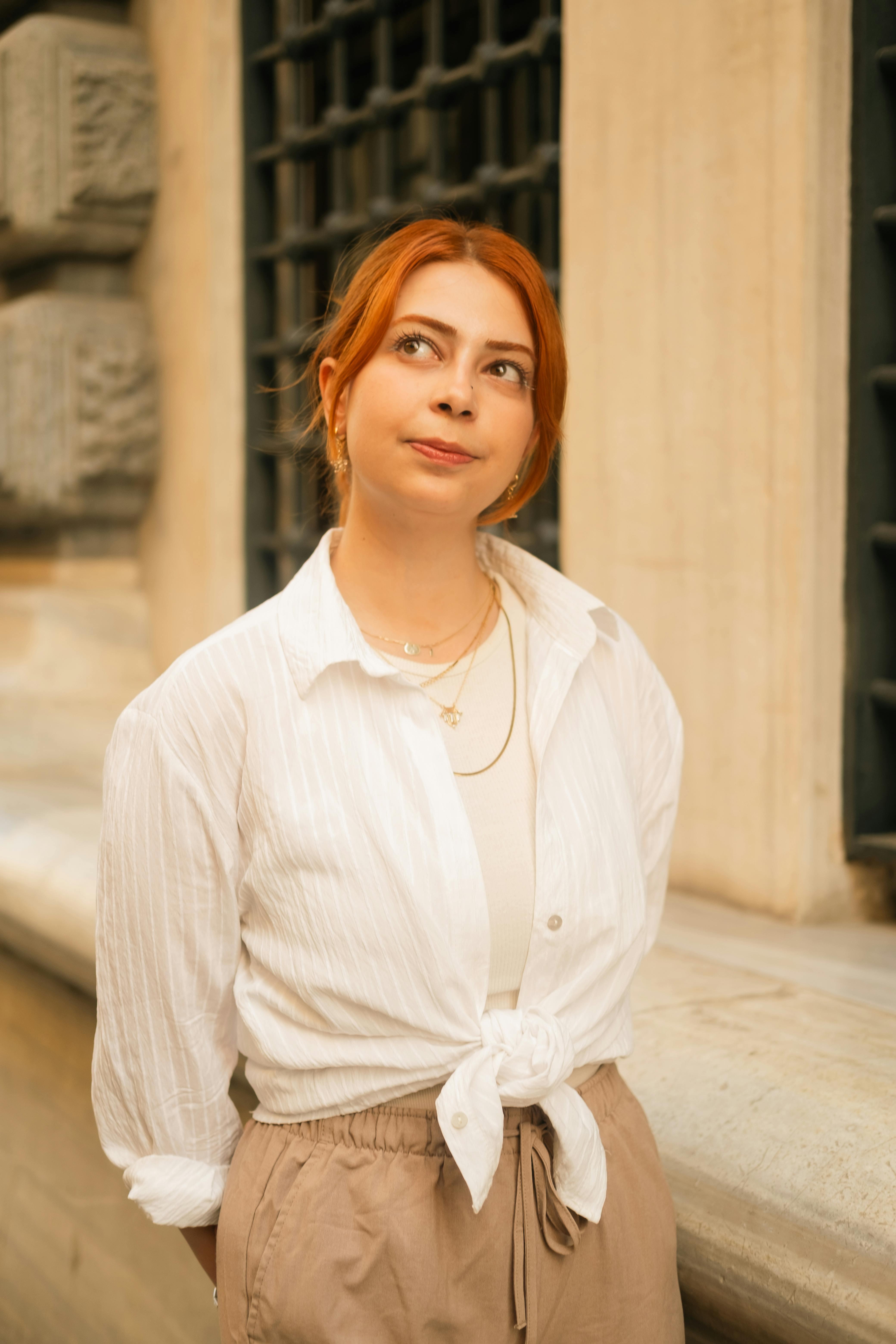 Portrait of a stylish woman with red hair in Istanbul, Türkiye, against a textured building background.