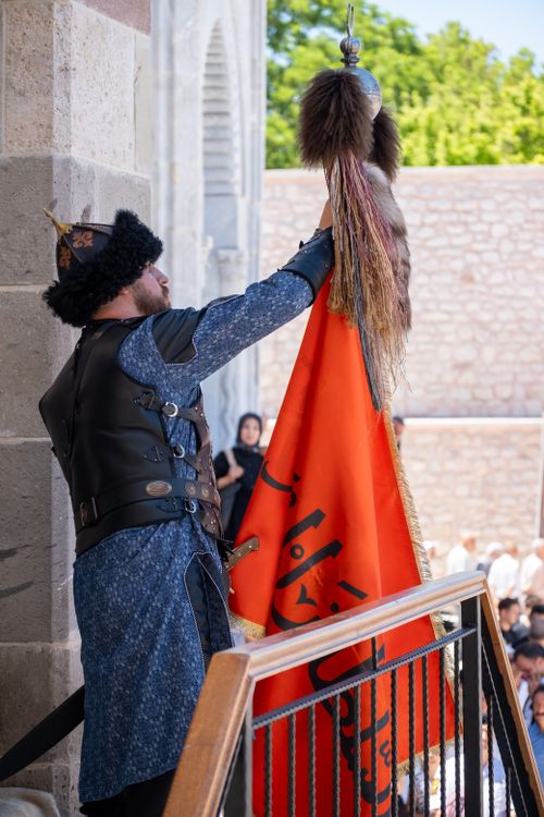 Free A person in traditional attire holds a flag during a historical reenactment in Konya, Türkiye. Stock Photo