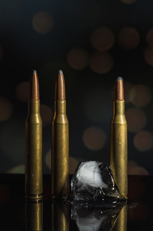 Free Dramatic still life of bullets and ice cube against dark bokeh background, symbolizing conflict. Stock Photo