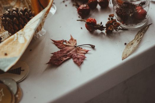 Dried maple leaf surrounded by autumn elements on a tabletop.