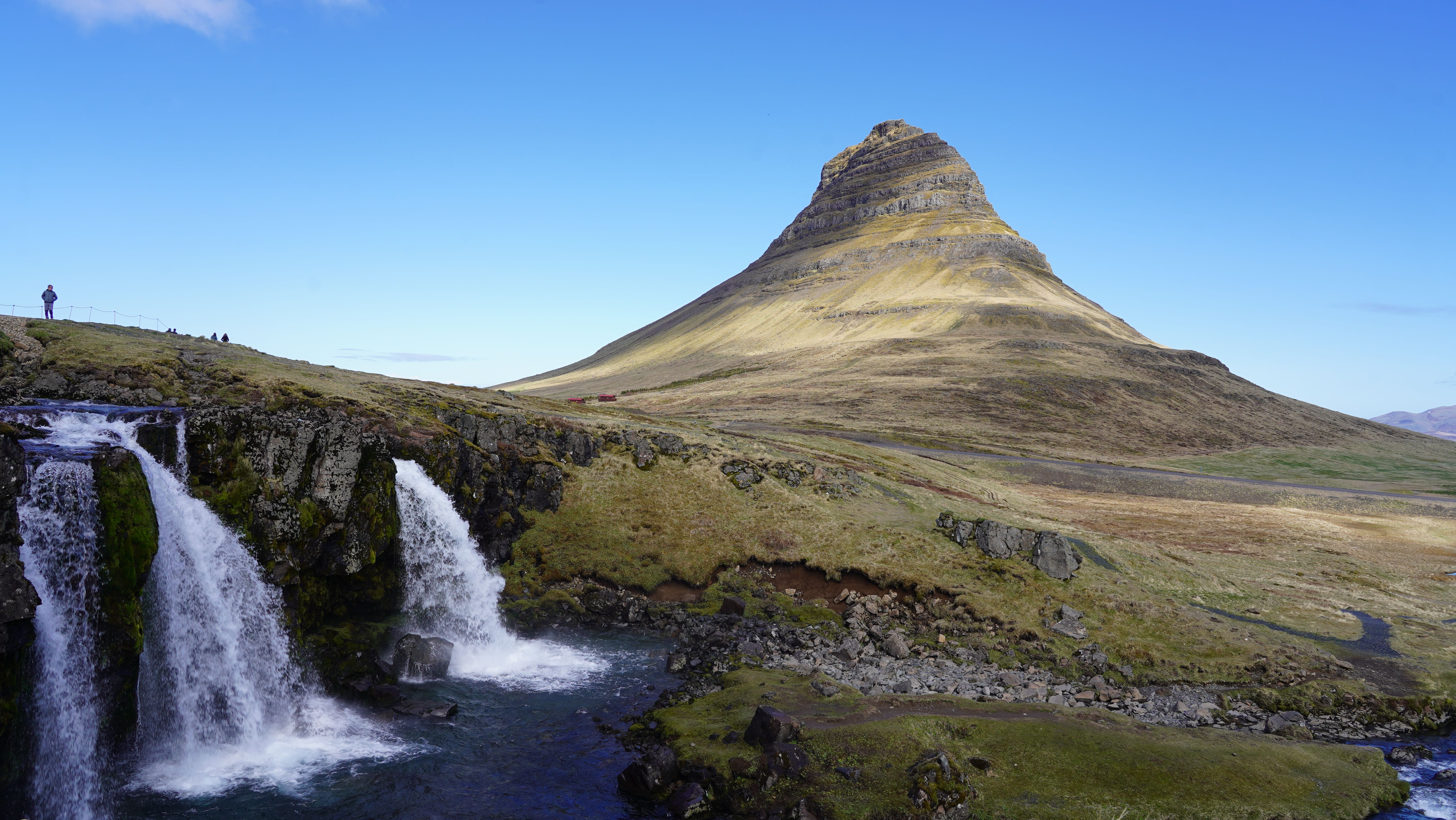 Dramatic shot of Kirkjufell mountain with cascading waterfall in Iceland under a clear blue sky. - Snæfellsnes