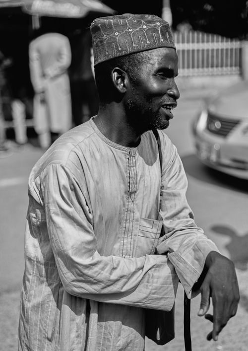 Free Black and white portrait of a smiling man in traditional clothing on a street. Stock Photo
